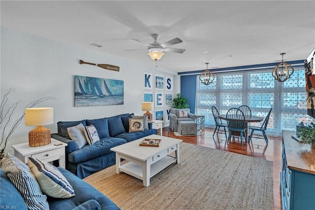 living area with visible vents, wood finished floors, and ceiling fan with notable chandelier