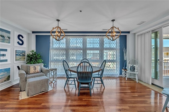 dining space with wood finished floors, visible vents, and an inviting chandelier