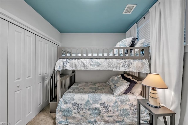 carpeted bedroom featuring a closet and visible vents