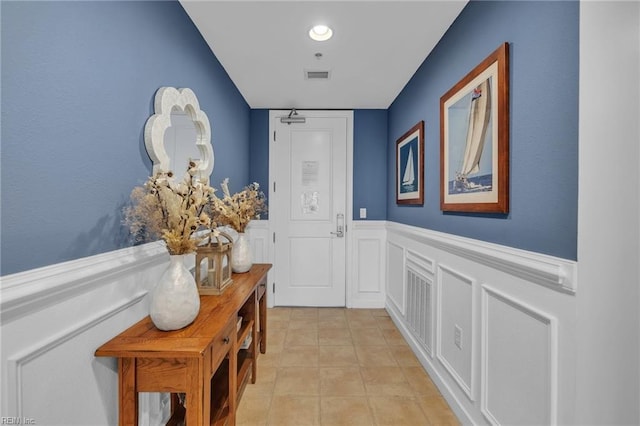 doorway featuring wainscoting, visible vents, and light tile patterned floors