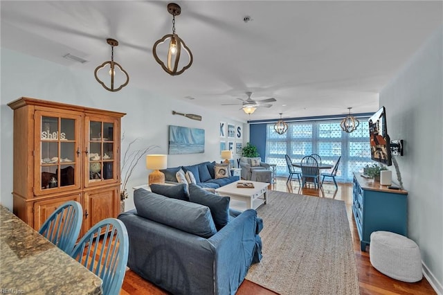 living area with visible vents, wood finished floors, and ceiling fan with notable chandelier