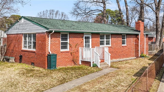 view of front of home featuring brick siding, a shingled roof, a chimney, fence, and a front yard