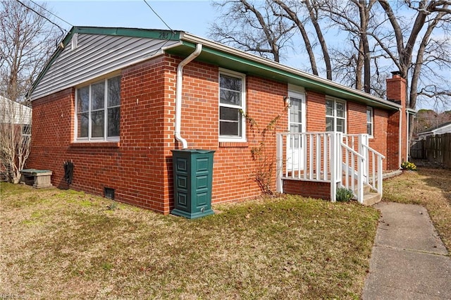 exterior space with a yard, brick siding, a chimney, and fence