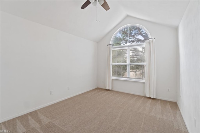 spare room with vaulted ceiling, ceiling fan, baseboards, and light colored carpet