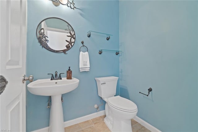 half bathroom featuring tile patterned flooring, toilet, and baseboards