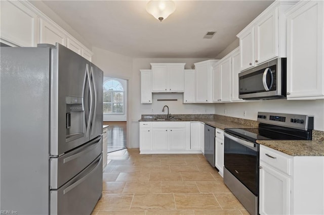 kitchen with appliances with stainless steel finishes, a sink, visible vents, and white cabinets