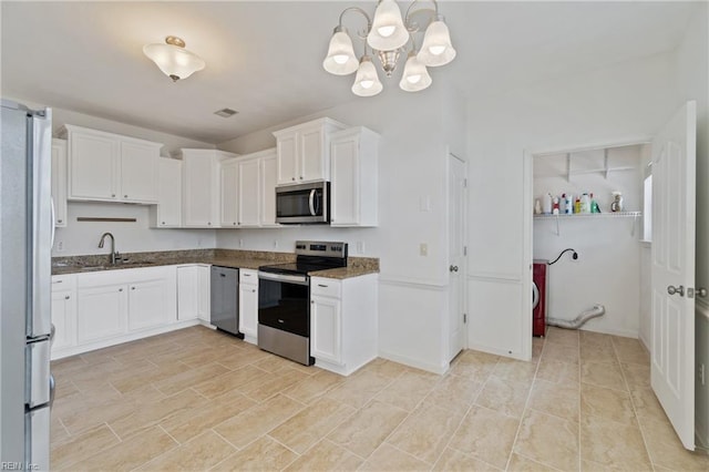 kitchen with stainless steel appliances, white cabinetry, a sink, dark stone counters, and baseboards