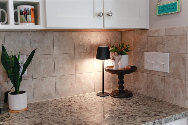 room details with light stone counters, decorative backsplash, and white cabinets