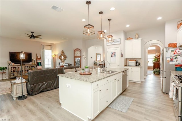 kitchen with a sink, visible vents, arched walkways, and light wood-style floors