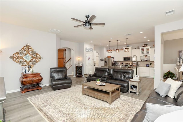 living area with recessed lighting, visible vents, arched walkways, and light wood finished floors