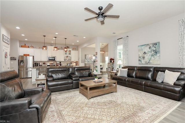 living area with recessed lighting, ceiling fan, and light wood finished floors