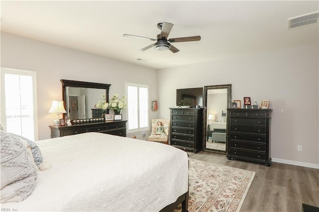 bedroom featuring ceiling fan, wood finished floors, visible vents, and baseboards