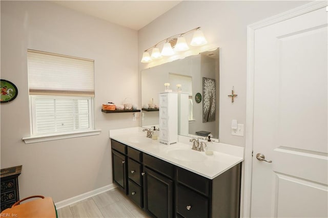 bathroom featuring a sink, baseboards, and double vanity