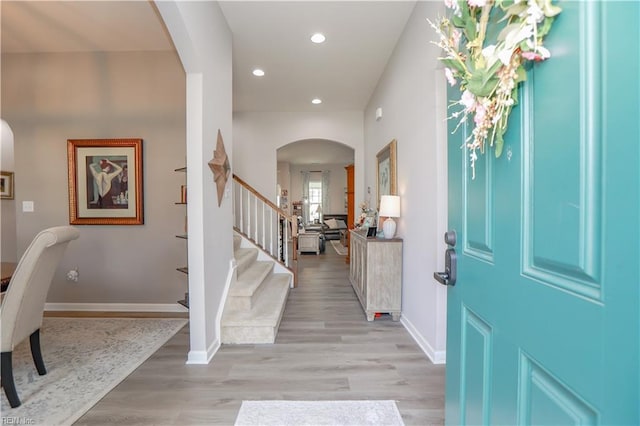 entryway with arched walkways, recessed lighting, light wood-style flooring, and baseboards