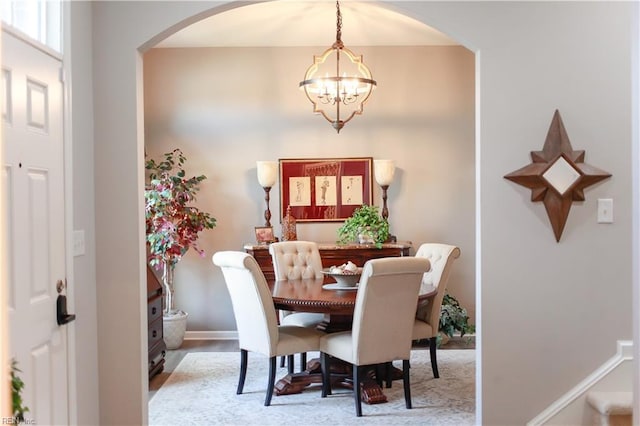 dining space with arched walkways, baseboards, and an inviting chandelier