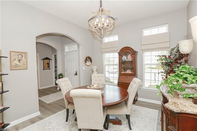 dining room with light wood-type flooring, baseboards, a notable chandelier, and a healthy amount of sunlight