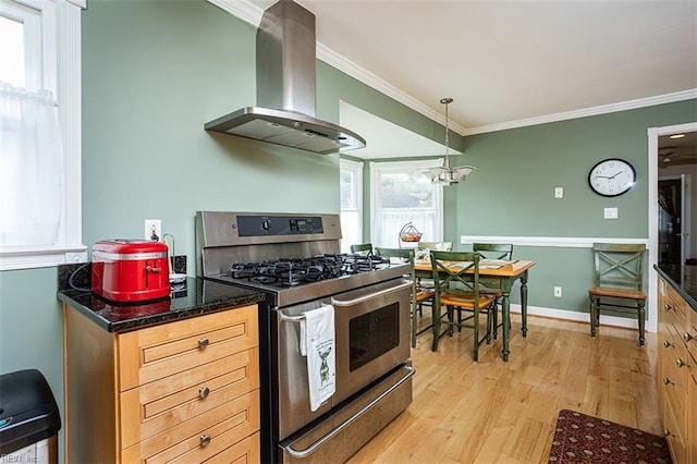 kitchen with light wood-type flooring, gas range, crown molding, and wall chimney range hood