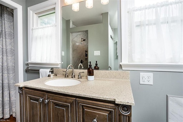 full bath with tiled shower and vanity