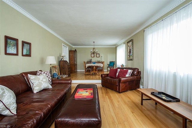 living area with light wood-style floors, crown molding, and a notable chandelier