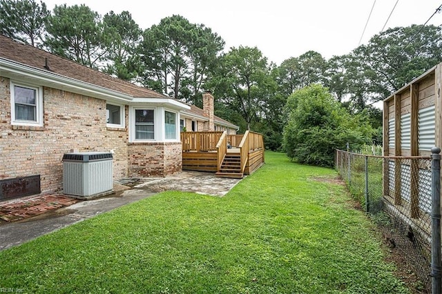 view of yard featuring fence, a wooden deck, and central AC unit