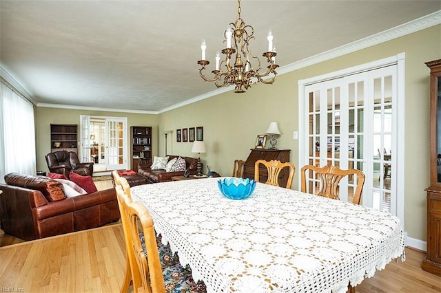 dining area with ornamental molding, french doors, light wood-style floors, and a healthy amount of sunlight