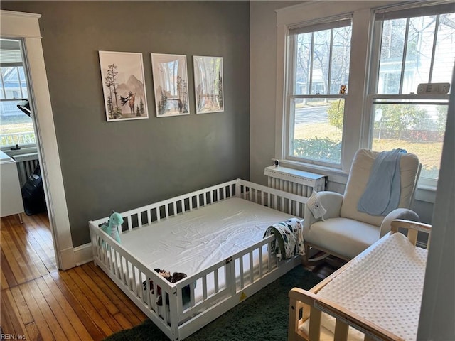 bedroom with multiple windows, baseboards, and hardwood / wood-style flooring