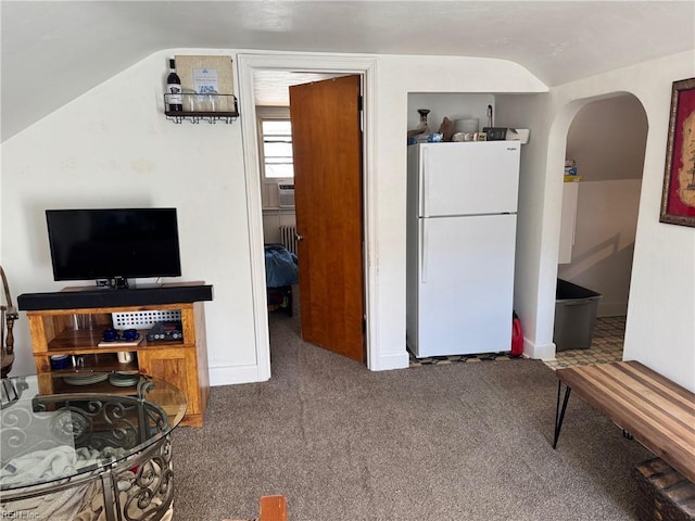 kitchen featuring lofted ceiling, arched walkways, cooling unit, freestanding refrigerator, and carpet