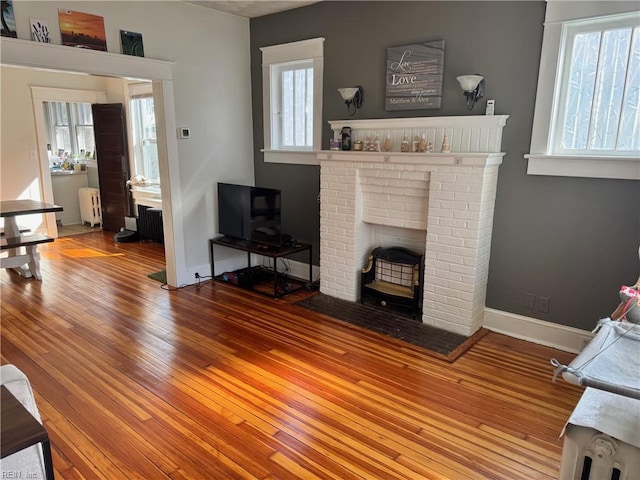 living room featuring radiator, a fireplace, baseboards, and hardwood / wood-style flooring