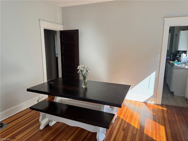 dining area with wood-type flooring and baseboards