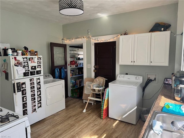 laundry area featuring light wood finished floors, laundry area, washer and dryer, and a sink