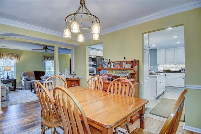 dining space with ornamental molding, ceiling fan, and light wood finished floors