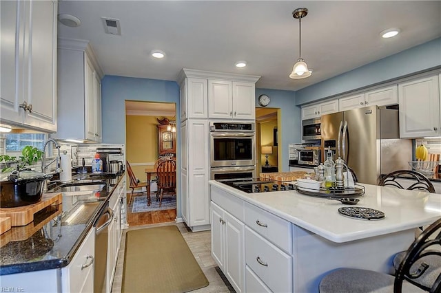 kitchen featuring stainless steel appliances, visible vents, white cabinets, backsplash, and a kitchen bar