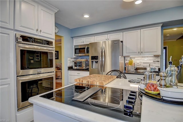 kitchen with stainless steel appliances, tasteful backsplash, recessed lighting, and white cabinets