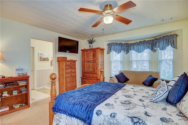 bedroom featuring carpet floors, wainscoting, visible vents, and a ceiling fan