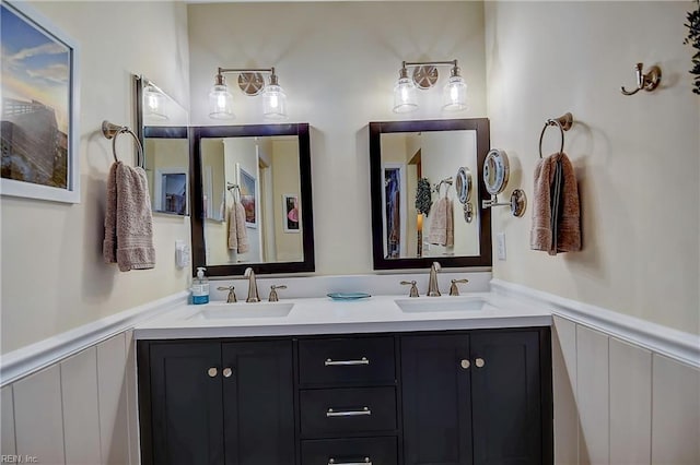 bathroom with double vanity, a wainscoted wall, and a sink