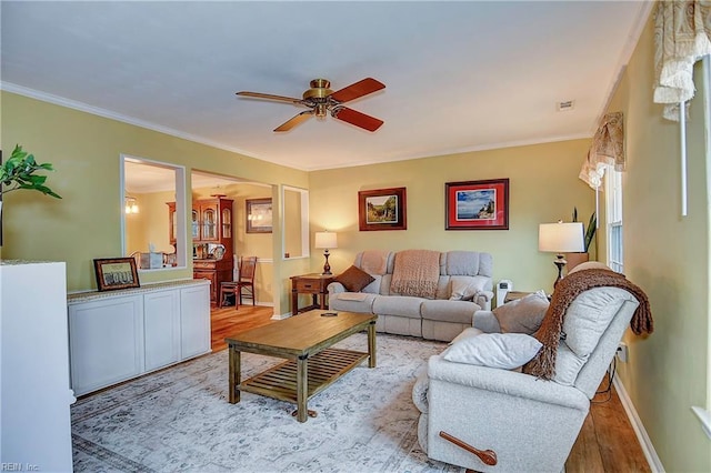 living room with ornamental molding, wood finished floors, a ceiling fan, and baseboards