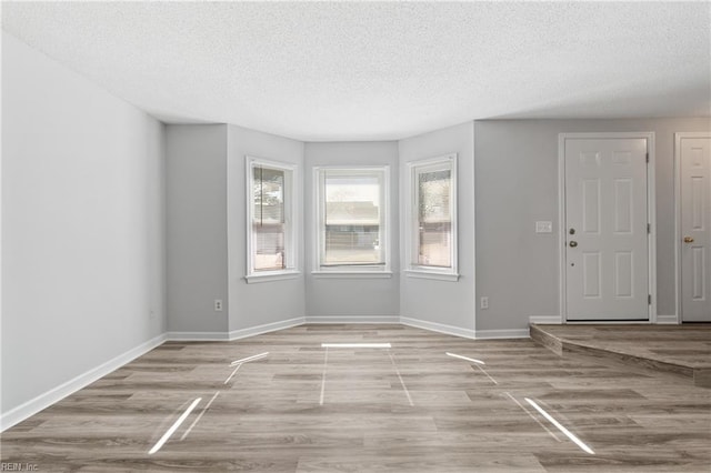 interior space with a textured ceiling, wood finished floors, and baseboards