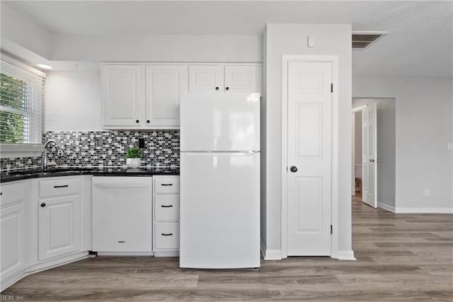 kitchen with white appliances, dark countertops, and white cabinetry