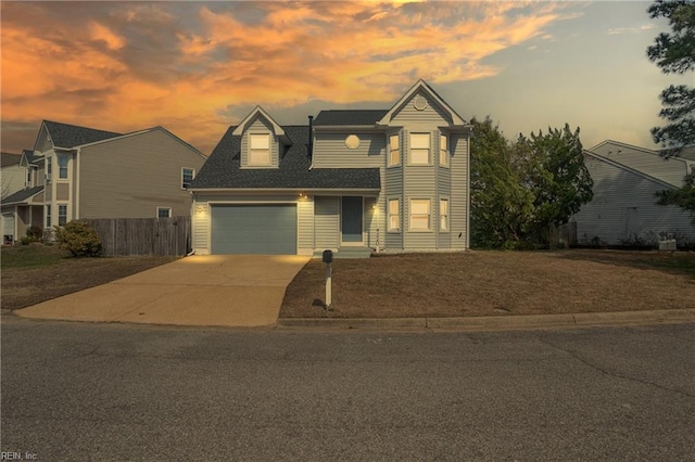 traditional home featuring a garage, driveway, and fence