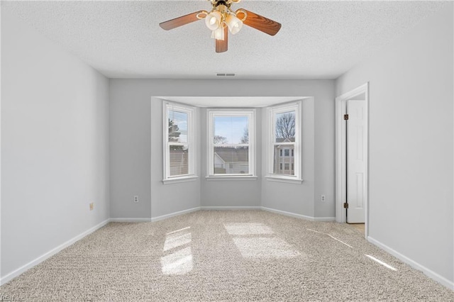 unfurnished room with baseboards, carpet, visible vents, and a textured ceiling