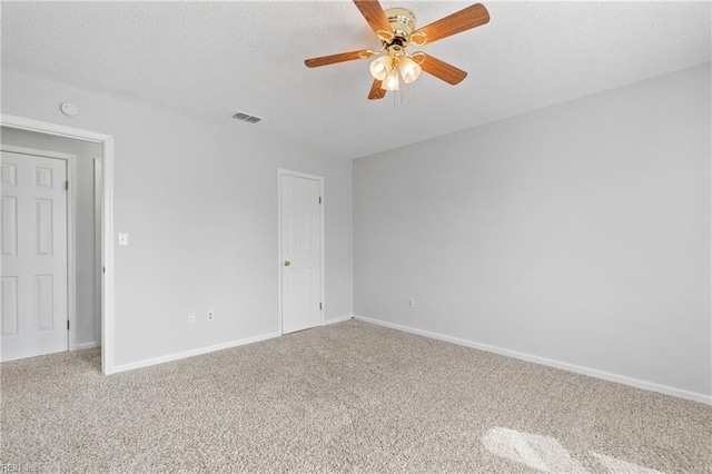 unfurnished room with carpet, visible vents, a textured ceiling, and baseboards