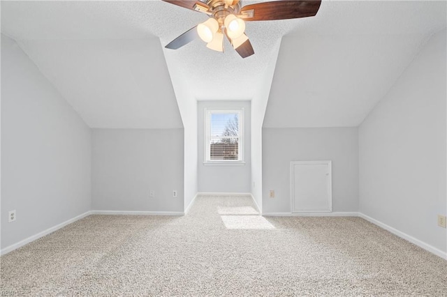 additional living space featuring a textured ceiling, vaulted ceiling, carpet flooring, and baseboards