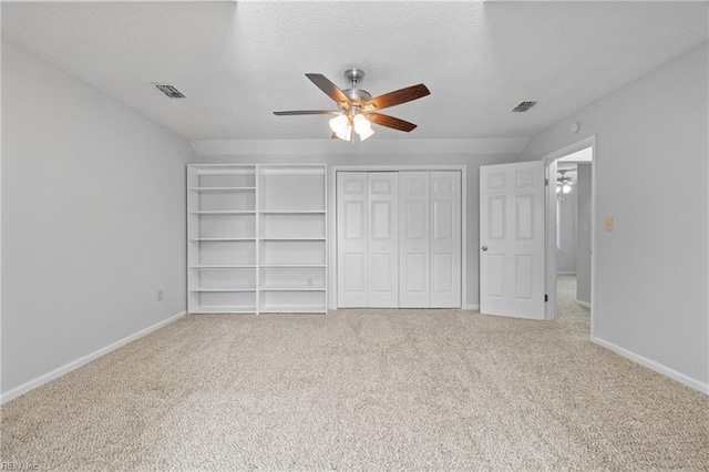 unfurnished bedroom featuring carpet, visible vents, a textured ceiling, and baseboards