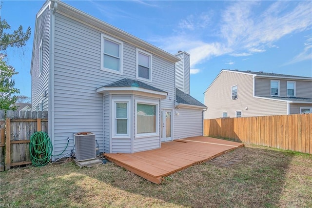 back of property with a fenced backyard, a lawn, and central AC