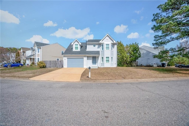 view of front of home with a front yard, driveway, an attached garage, and fence