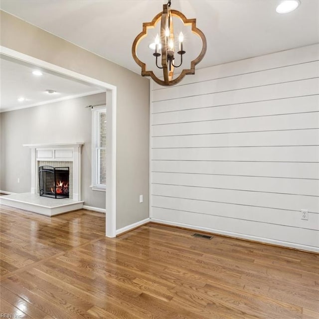 interior space with a warm lit fireplace, baseboards, wood finished floors, and recessed lighting