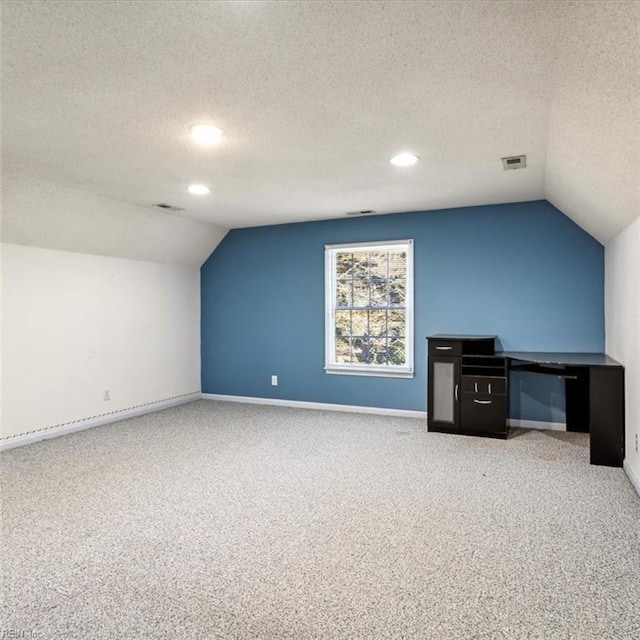 additional living space with baseboards, visible vents, vaulted ceiling, and carpet flooring