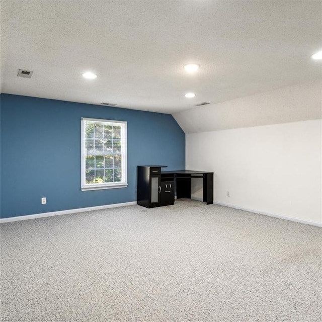 unfurnished office with lofted ceiling, carpet floors, a textured ceiling, and baseboards