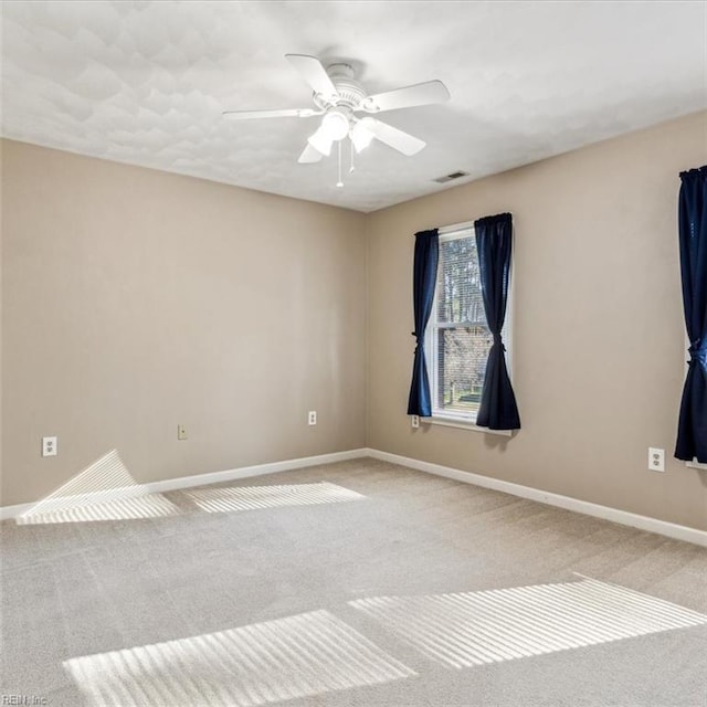 carpeted spare room with a ceiling fan, visible vents, and baseboards