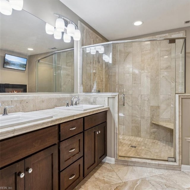 bathroom with double vanity, a stall shower, a sink, and visible vents